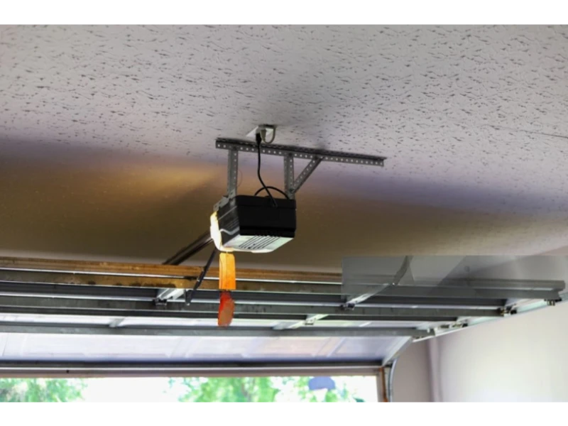 Overhead door opener motor and rail mounted to the ceiling with emergency release handle.