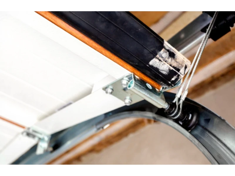 Garage Door Cable, Drum & Bottom Bracket Repair in Alvin, TX – Bottom bracket with lift cable attachment and mounting hardware on a sectional garage door