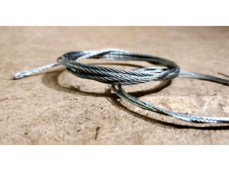 Garage Door Cable, Drum & Bottom Bracket Repair in Alvin, TX – New replacement garage door lift cable coiled and ready for installation