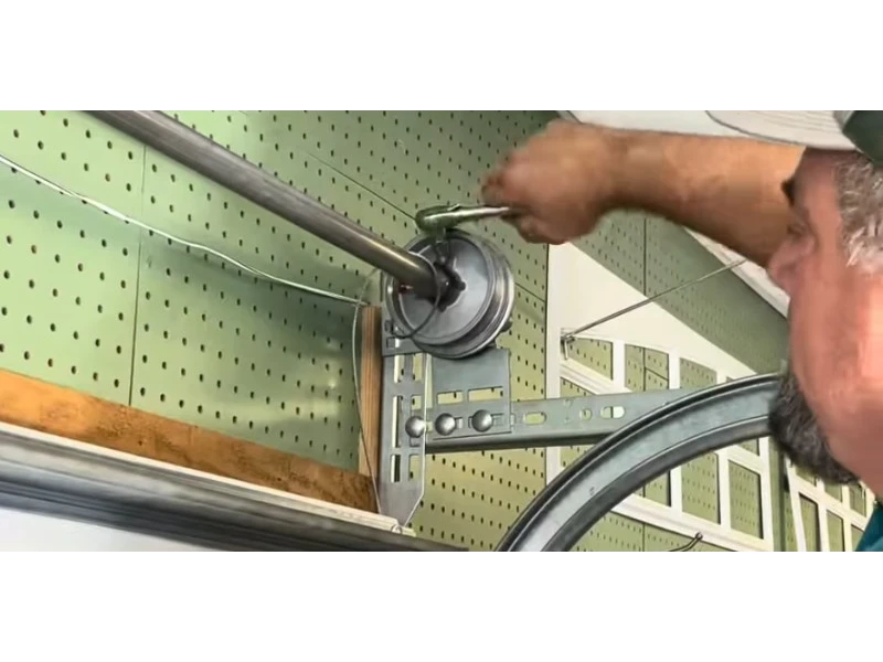 Technician adjusting garage door cable drum and torsion shaft for safe alignment in Alvin, TX.
