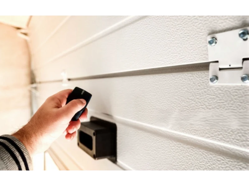Garage Door Keypad & Remote Programming in Alvin, TX – close-up of a hand using a garage door remote by the door panel.