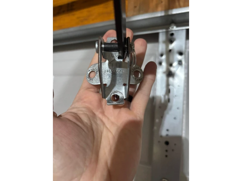 Garage door bottom bracket and cable attachment point inspected for safe operation in Alvin, TX.