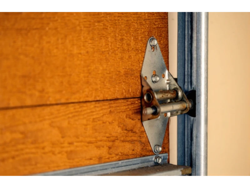 Garage door hinge and roller bracket close-up on a wood door near the track in Alvin, TX.