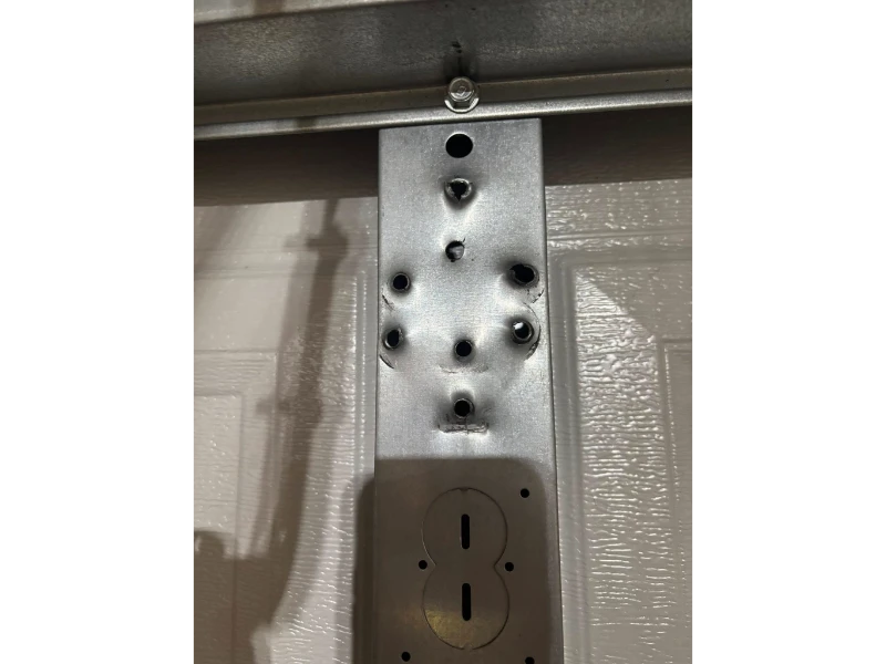 Garage door reinforcement mounting plate with hardware holes for secure track and hinge attachment in Alvin, TX.