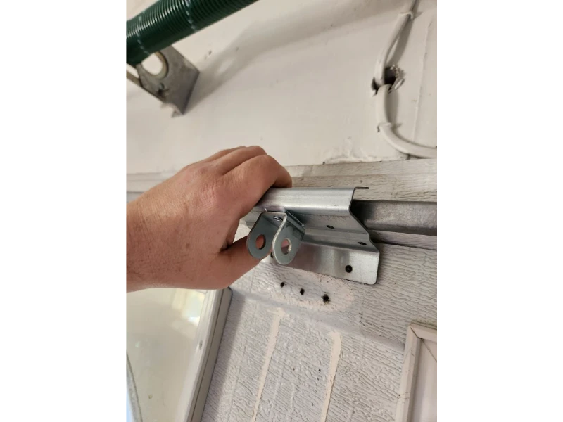 Garage door track end stop bracket installed to prevent rollers from rolling out in Alvin, TX.
