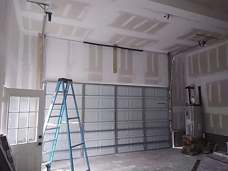 Garage door track and hardware inspected in an unfinished garage during a scheduled tune-up in Alvin, TX.