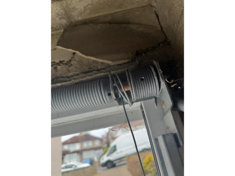 Close-up of a damaged extension spring and tangled lift cable needing repair in Alvin, TX.