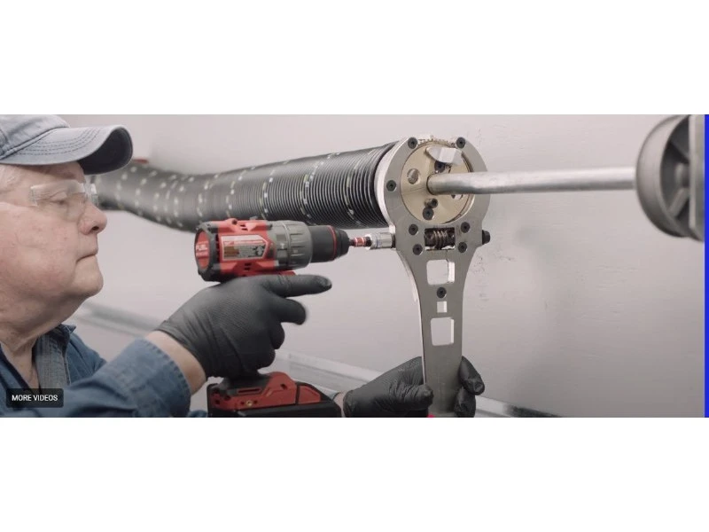 Technician winding a torsion spring with a winding tool for safe spring replacement in Alvin, TX.