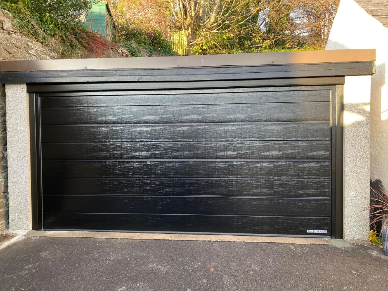 Black modern sectional garage door installed in a single-car opening (Alvin, TX).