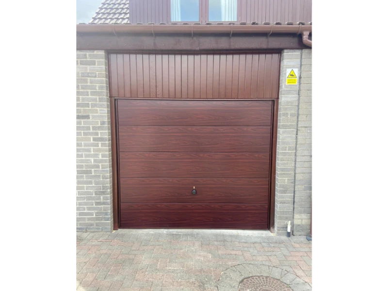 Woodgrain brown garage door replacement with matching upper cladding (Alvin, TX).